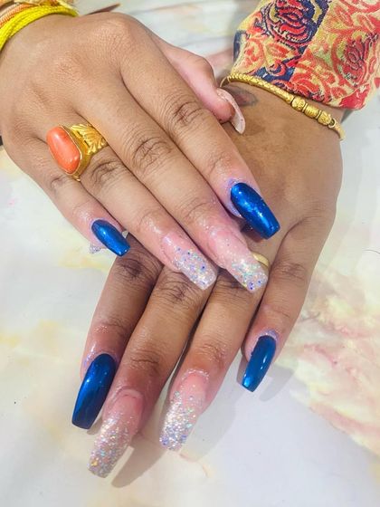 A striking combination of metallic blue chrome and sparkling silver glitter. This student work shows how to pair bold colors and textures for a glamorous, high-impact nail design.