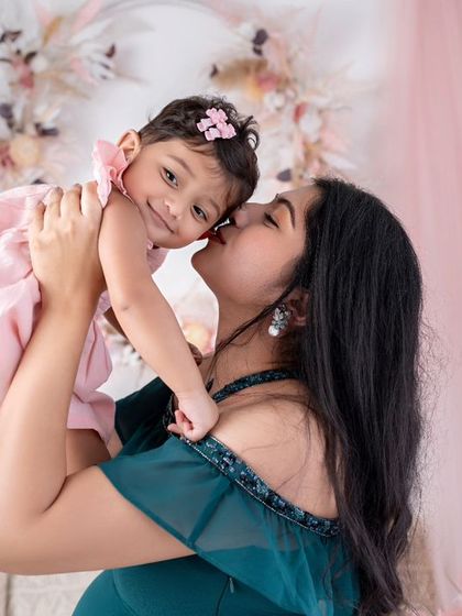 A mother lifts her daughter in the air, both of them full of smiles. A moment of pure joy.