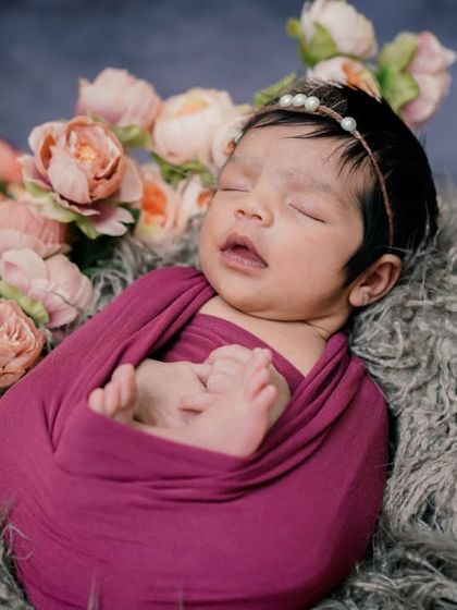 A floral embrace. This swaddled baby, nestled in a bed of fur and flowers, looks like a precious gem.