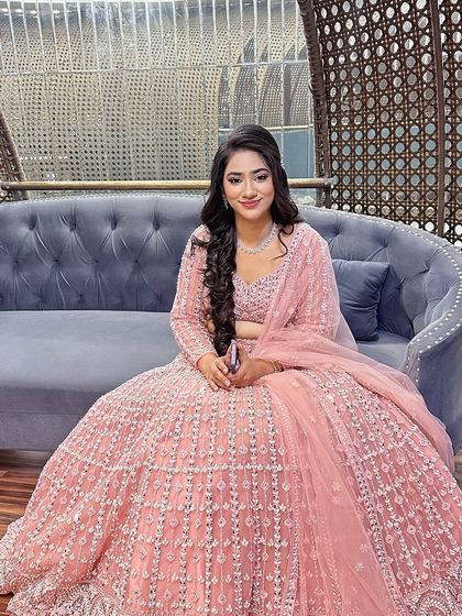 A pretty-in-pink engagement look. The client's makeup is soft and romantic, with a side-swept hairstyle featuring long, flowing curls.