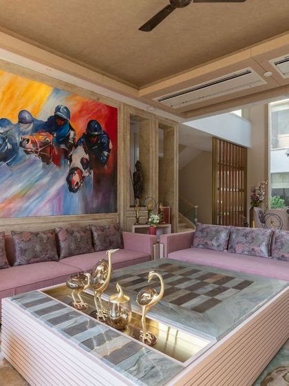 This vibrant living room uses bold color and art to create a dynamic atmosphere. A large, colorful painting serves as the focal point, complemented by pink sofas and a unique checkerboard coffee table, showcasing a playful yet luxurious design approach.