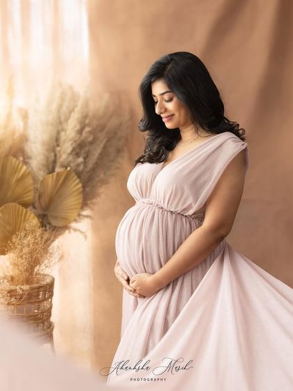 A full-length portrait in a flowing mauve gown, with the fabric creating a beautiful train behind the mother-to-be.