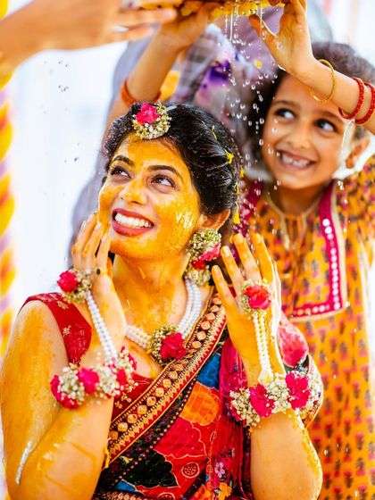 The bride looking up with a huge smile as she's showered with blessings and flowers.