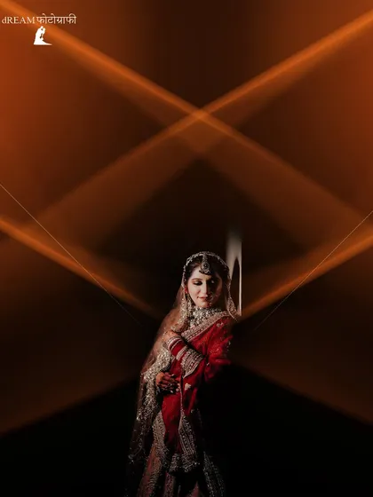 An artistic bridal portrait of Khushbu, framed by creative light streaks that draw attention to her elegant pose and traditional red lehenga.