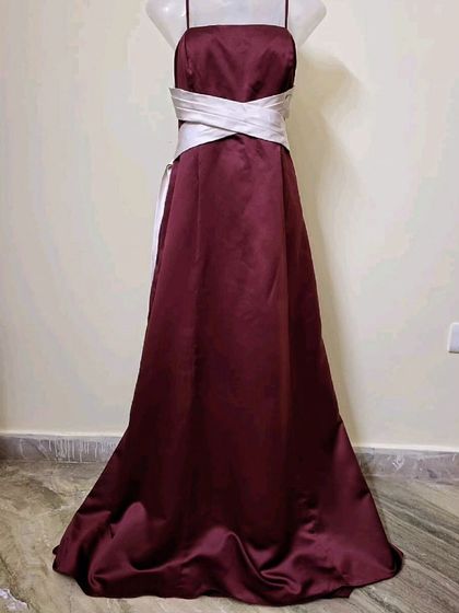 A simple yet elegant maroon satin gown with a contrasting white sash. This is a classic and timeless silhouette, perfect for a formal party or event.