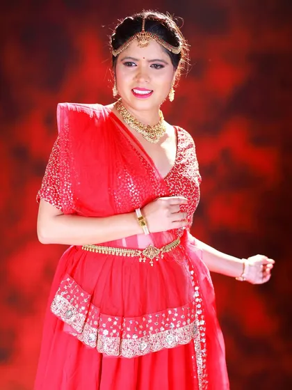A mid-shot of the model in a red lehenga. The pose is joyful and expressive, and the studio lighting is set to create a celebratory mood.