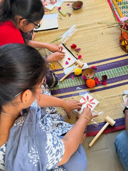 Participants in our workshop carefully arranging flower petals on their cards before the pounding begins. This initial design phase is where each artist's unique vision starts to take shape.