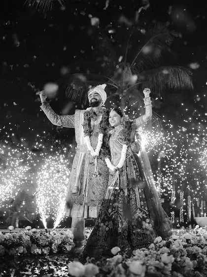 A grand exit surrounded by the sparkle of celebration. This photograph captures the triumphant joy of the newlyweds as they are celebrated by their loved ones, a perfect end to the ceremony.