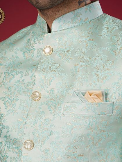 A close-up of a pastel blue brocade jacket, showcasing its luxurious texture and elegant buttons.
