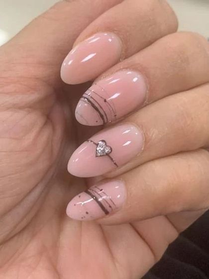 A simple and sweet design on pink oval nails, with a tiny heart-shaped rhinestone as the centerpiece of a delicate, hand-drawn design.