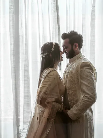 A romantic silhouette of the couple about to kiss, framed against a softly lit curtain, creating an intimate and timeless feel.