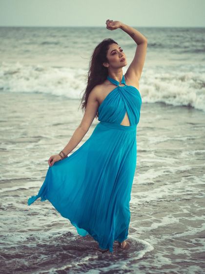A graceful and powerful pose in the ocean. The flowing dress mimics the movement of the waves, creating a harmonious composition.