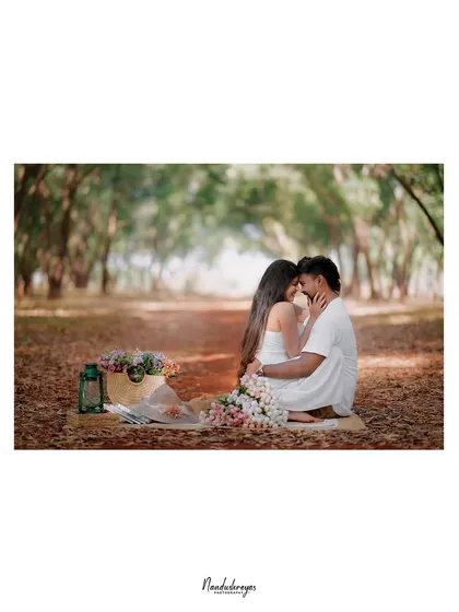 An intimate moment from a picnic scene, with the couple close together on a blanket in the woods.