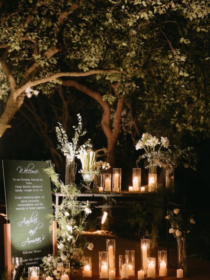 The welcome area for the "Into the Woods" dinner, where a simple sign was made magical with an installation of candles in varying heights, nestled among fresh white flowers.