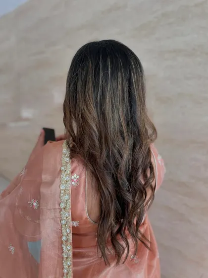 Soft waves and a beautiful peach-toned saree for this wedding guest. The hairstyle is simple, elegant, and lets her highlights shine.