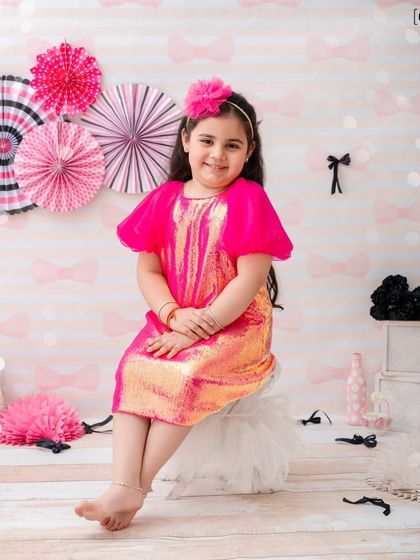 Posing like a little model, this girl is confident and cute in her sparkly dress and pink-themed set.