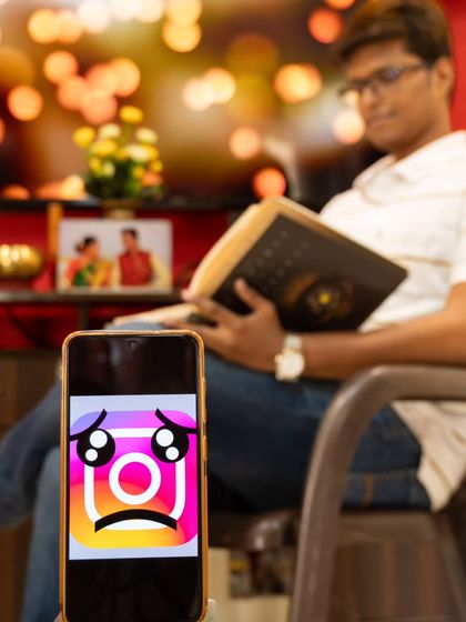 Part of a creative series on the theme of a 'social media detox'. The phone in the foreground with a sad face contrasts with the person peacefully reading a book in the background.