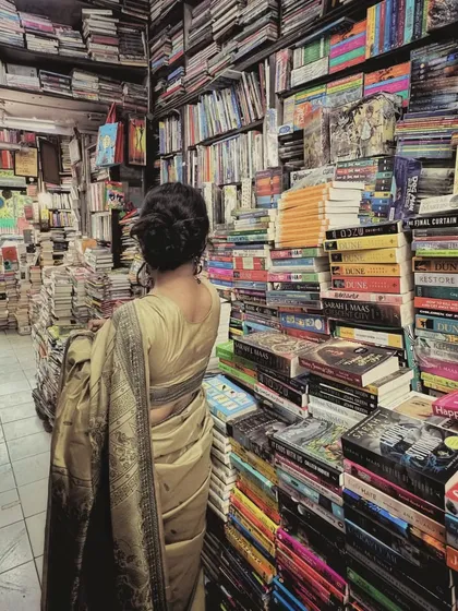 From the back, you can see the simple, elegant bun hairstyle and the way the saree drapes as I browse the bookshelves. Every detail is planned to contribute to the overall story of the shoot.