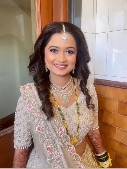 A close-up smiling portrait of the bride, showcasing her diamond jewelry and flawless makeup.