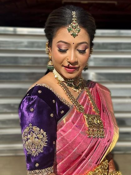 This bride's look is a beautiful blend of colour and tradition. The soft pink makeup with shimmery eyes complements her unique pink and purple Kanjivaram, creating a look that is both elegant and full of personality.
