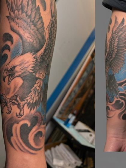 A full eagle sleeve tattoo with a blue sky background. The design wraps around the forearm, showing the eagle in a dynamic pose. It's a symbol of power and freedom that makes a bold statement.