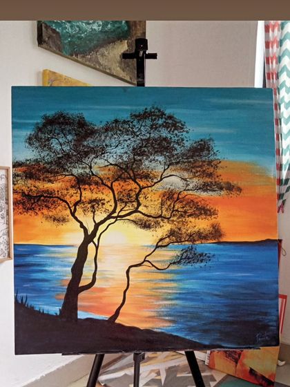 A beautiful sunset seascape on canvas. The silhouette of the tree against the vibrant orange and blue sky creates a peaceful and contemplative mood, perfect for any living space.
