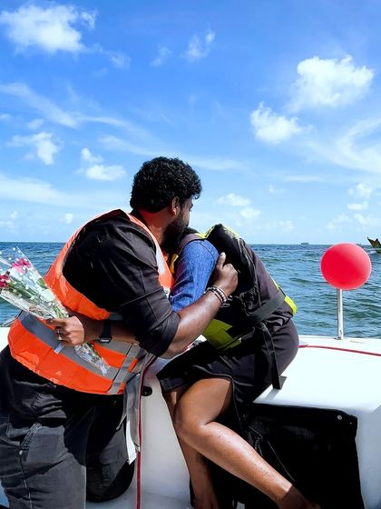 A beautiful proposal moment on a yacht, with the groom-to-be presenting a bouquet of roses.