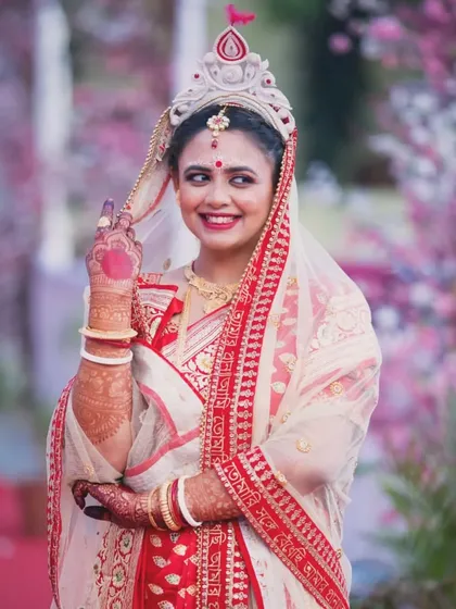 A candid, smiling portrait of a bride during her Bengali wedding ceremony, capturing her natural joy.