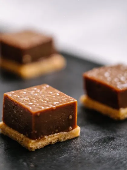 Milk chocolate fudge on a vanilla sable biscuit. This sweet canapé offers a delightful contrast of creamy fudge and a crisp, buttery base.