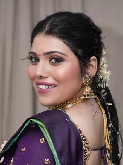 A happy, over-the-shoulder smile. This candid moment shows how the makeup looks natural and radiant, capturing her joyful spirit.