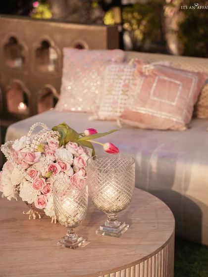 An intimate seating nook with plush pink cushions and delicate floral arrangements, showcasing the thoughtful details of the wedding design.
