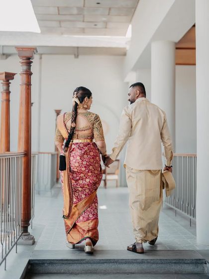 A shot from behind, showing the couple walking away. This angle highlights the intricate braid of the bride and the elegant fall of both their traditional outfits.