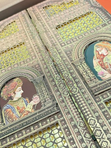 The full gate-fold view of the heritage card, showing the bride and groom portraits peeking through ornate jharokha-style windows.