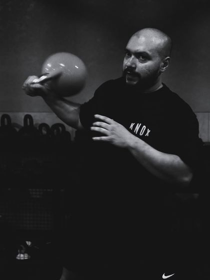 A powerful, focused shot of a member during a kettlebell workout. The black and white filter highlights the intensity and dedication of our crew.