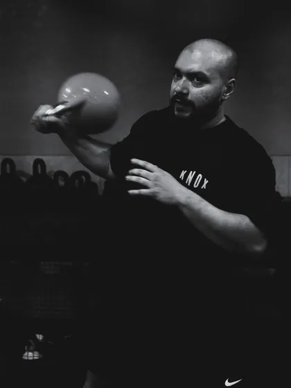 A dramatic, black and white photo of a coach mid-kettlebell flow, capturing the intensity and focus of our training.