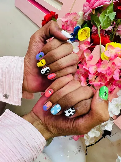 A fun and eclectic set of "random nail art," where each nail has a unique, hand-painted design including a smiley face, yin-yang, cow print, and more.