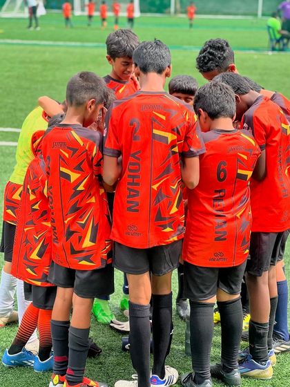 A team huddle before a big game in the Mini Dribblers League. The focus and unity are palpable.