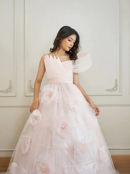 A detailed shot of the 'Carol' gown's bodice, highlighting the intricate wired draping and the soft texture of the 3D flowers on the skirt.