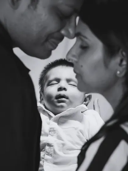 A black and white portrait capturing the intimate bond between parents and their newborn.