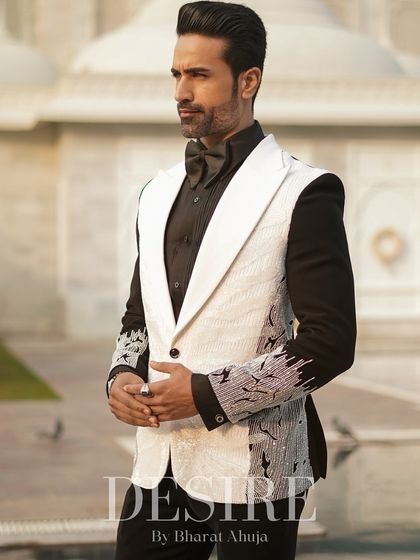 A profile view of the sleeveless white blazer against a majestic backdrop. The unique design and sharp tailoring create a look of modern royalty.