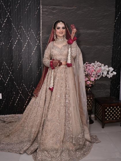 A full-length view of the bride in her breathtaking beige and red bridal outfit.