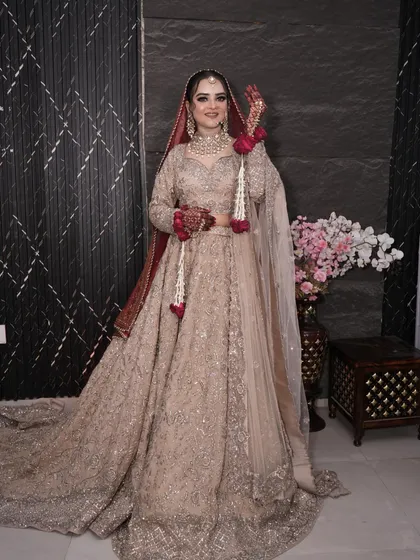 A full-length view of the bride in her breathtaking beige and red bridal outfit.