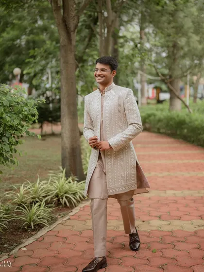 A candid, walking portrait of the groom with a bright, genuine smile. This shot captures his personality and dapper style in a relaxed, outdoor setting.