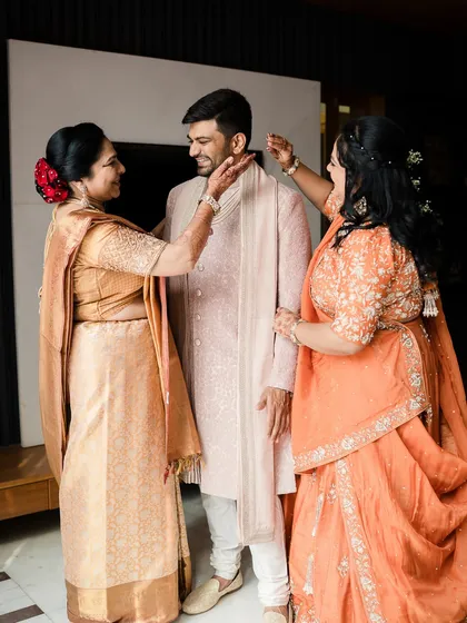 We believe in styling the entire family. Here, a groom shares a beautiful moment with his mother and aunt, both styled by us in elegant, coordinated attire that reflects their joy and importance on this special day.