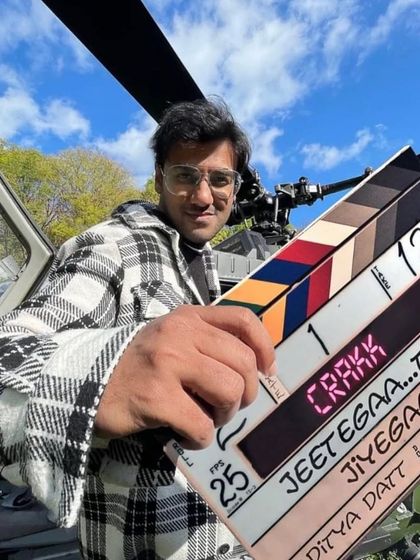 A crew member with the "Crakk" clapperboard in front of a helicopter. This image perfectly captures the scale and excitement of working on a big-budget action film.