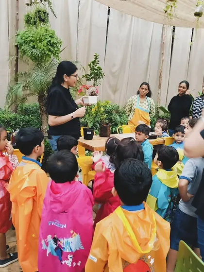 Learning by doing. Here, kids are gathered around for a hands-on demonstration during a planting workshop. These sessions are designed to be engaging and memorable for our little visitors.