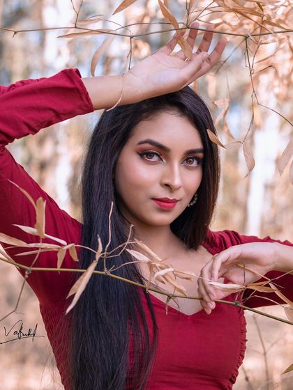 A close-up portrait where the model is framed by dry bamboo leaves. This composition adds texture and a natural element to the shot, drawing focus to her expressive eyes.