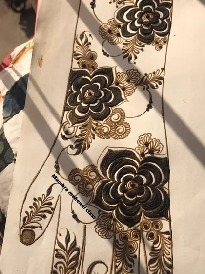 A beautiful floral design on a practice sheet, using black and brown henna for contrast.