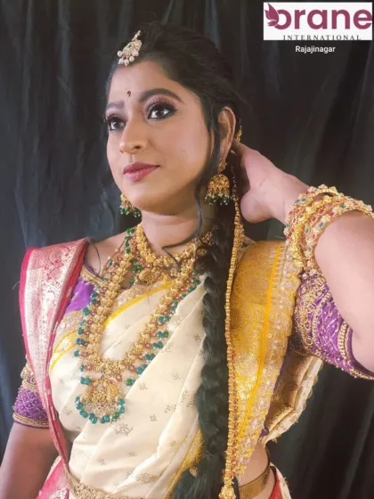 A beautiful profile shot showcasing a traditional bridal hairstyle. The hair is elegantly styled to support the heavy jewelry and veil, a key consideration in our bridal hairstyling training.
