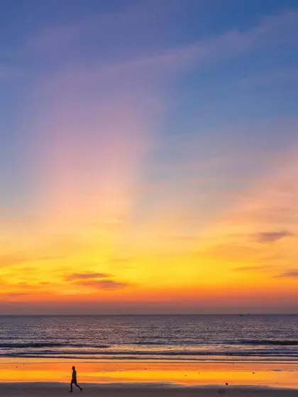 A duplicate of image 62, capturing the silhouette of a person walking along the beach under a stunningly colorful sunset.